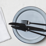 Lade das Bild in den Galerie-Viewer, schwarzes, schweres Besteck auf einem hellblauen Teller mit einer weißen Serviette